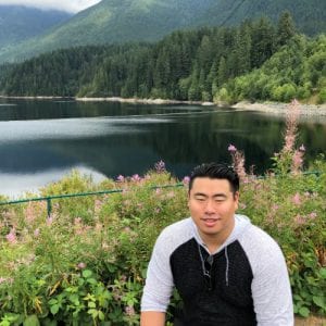 Gerald Yu outdoors next to a lake near mountains